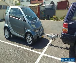 Smart car, fitted with tow frame for towing behind motorhome.